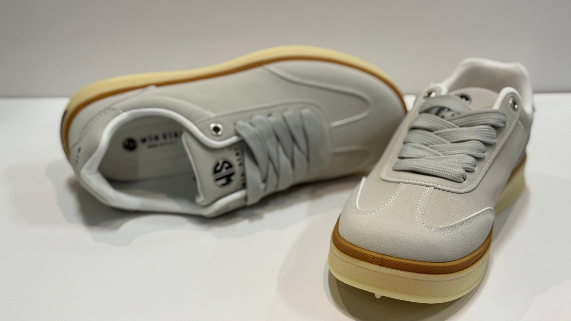 Pair of white sneakers with brown soles on a white background