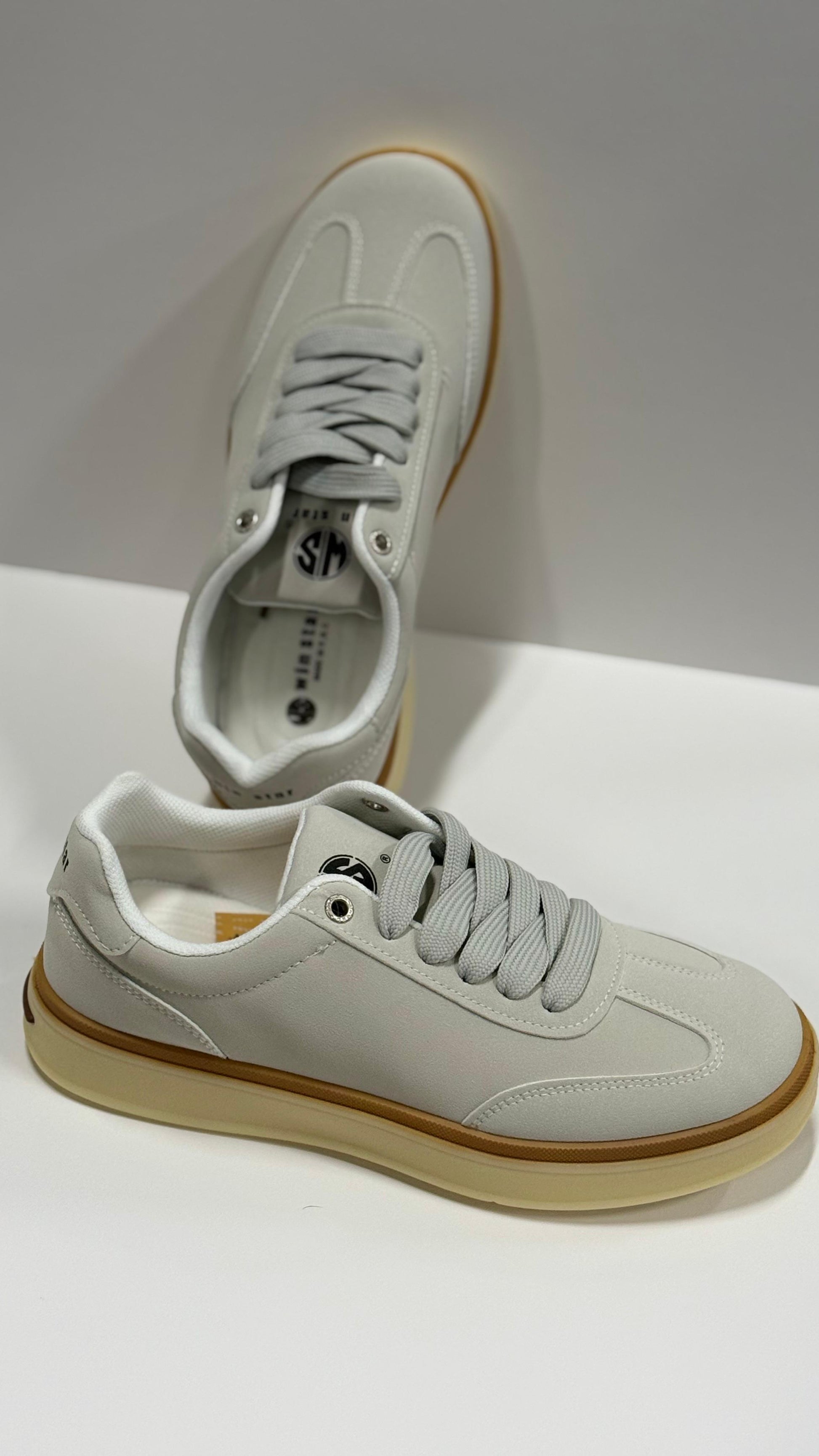 Pair of light gray sneakers with brown soles on a white background