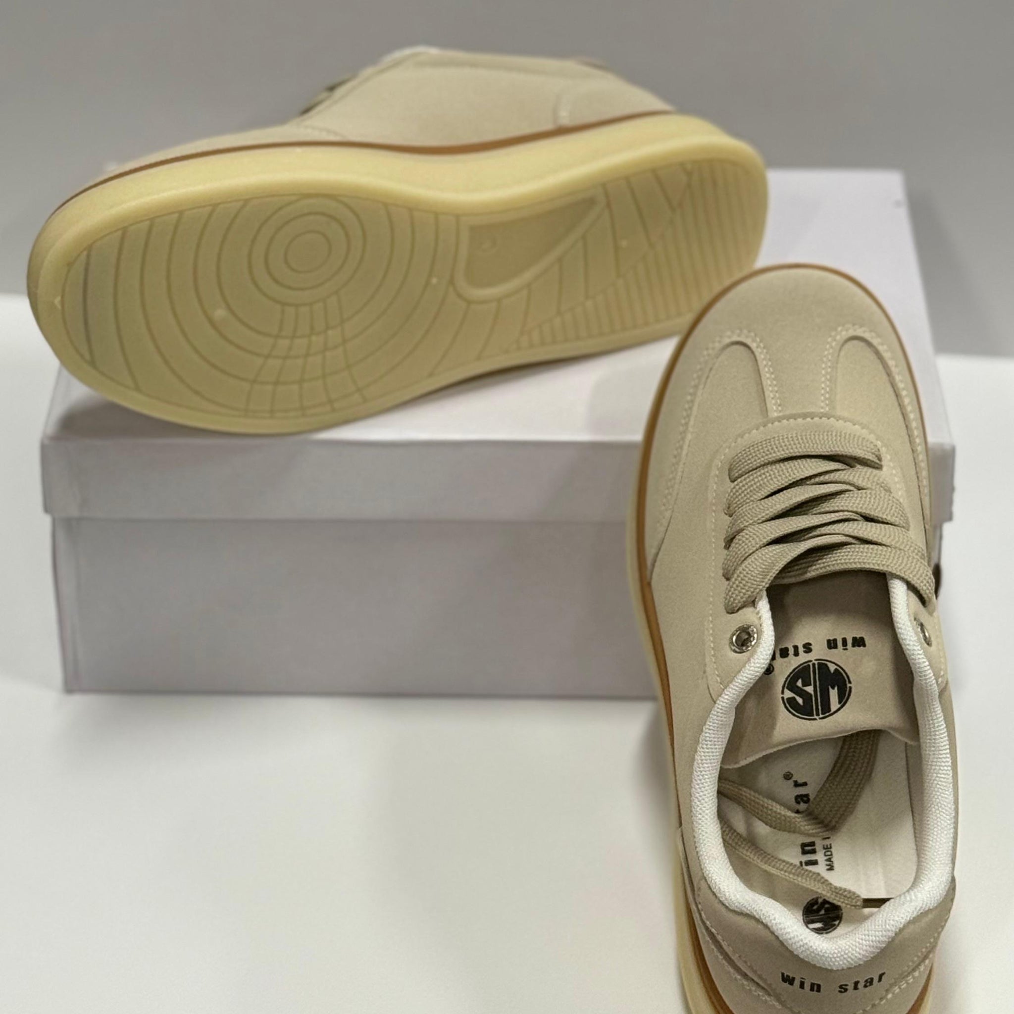 Beige sneakers with a white box on a light gray background